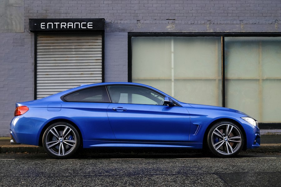 A blue coupe parked outside a building
