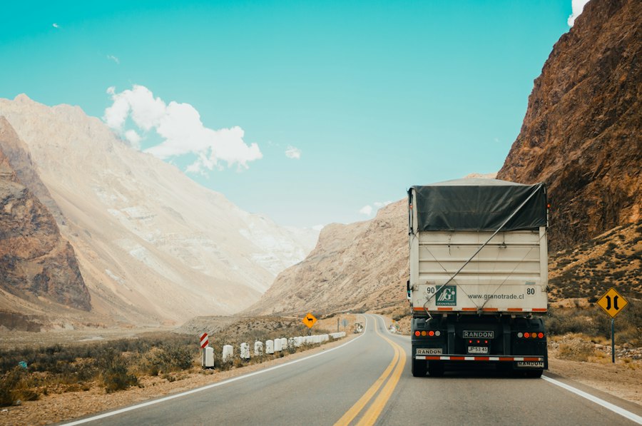 A truck driving along a winding mountain highway under a blue sky
