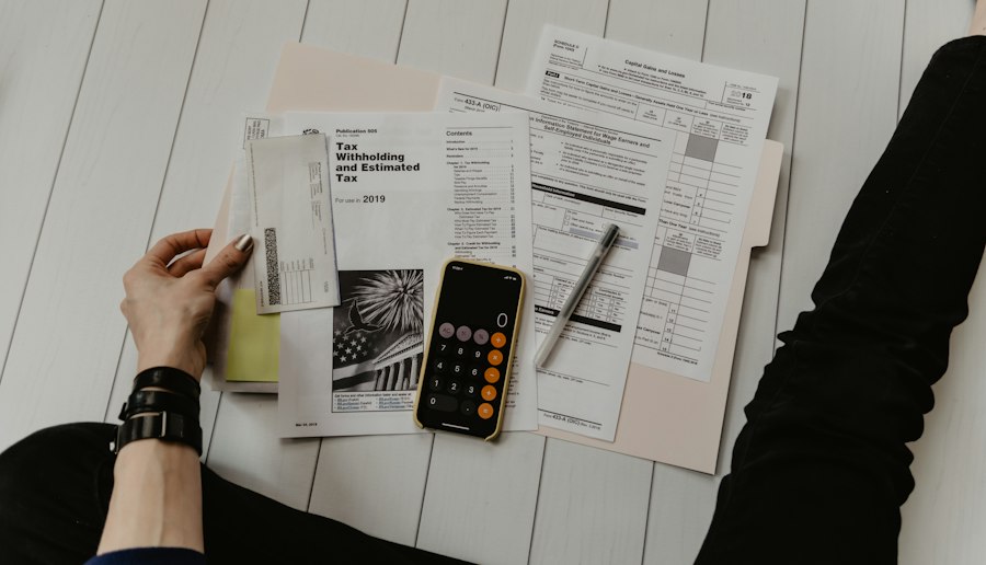 Papers, a calculator, and a hand holding a pen on a desk